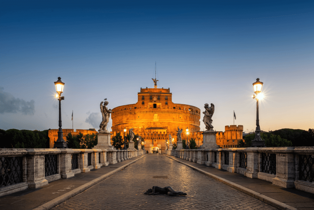 Castel Sant’Angelo illuminated at dusk with statues on the bridge in Rome