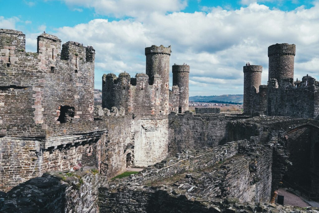 Stone towers and walls of Conwy Castle in Wales under blue sky