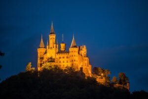 Majestic Hohenzollern Castle glowing against the night sky.