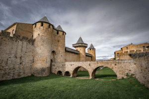 Carcassonne Castle with stone towers, walls, and bridge on a cloudy day