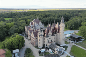 Aerial view of Moszna Castle surrounded by lush forest in Poland.