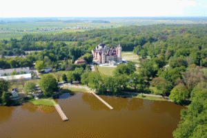 Aerial view of Moszna Castle surrounded by lakes and forest.