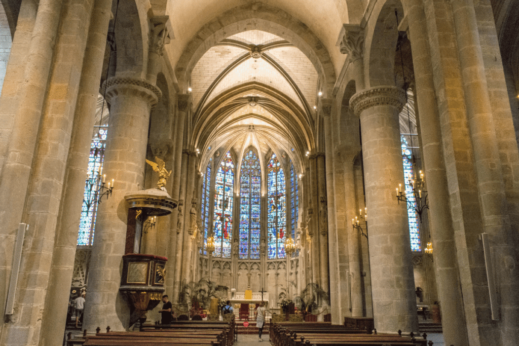 Gothic arches and stained glass windows inside Cathedral of Saint-Nazaire, Béziers.