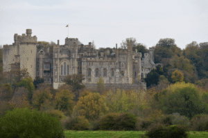 Arundel Castle above autumn woods in West Sussex, England, seen from a distance on an overcast day.