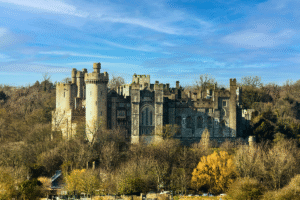 Arundel Castle towers above winter trees under blue sky in West Sussex, England.
