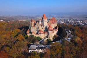 Aerial view of Burg Kreuzenstein castle above autumn forest near Leobendorf, Lower Austria, with red rooftops.