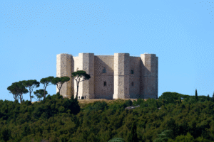 Castel del Monte rising above pines under clear Apulia sky.