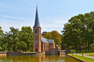 Lakeside chapel at Castle De Haar framed by trees and reflective moat