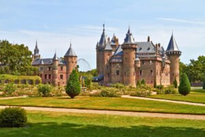 Castle De Haar beside manicured lawns and rose gardens under a blue sky