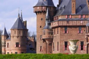 Castle De Haar towers and red-white shutters over grassy moat