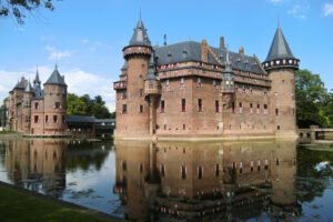 Castle De Haar reflected in tranquil moat under blue sky