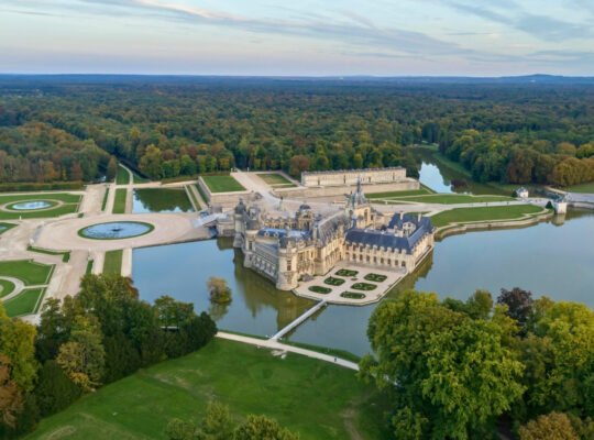 Aerial view of Chantilly Castle surrounded by gardens and moat