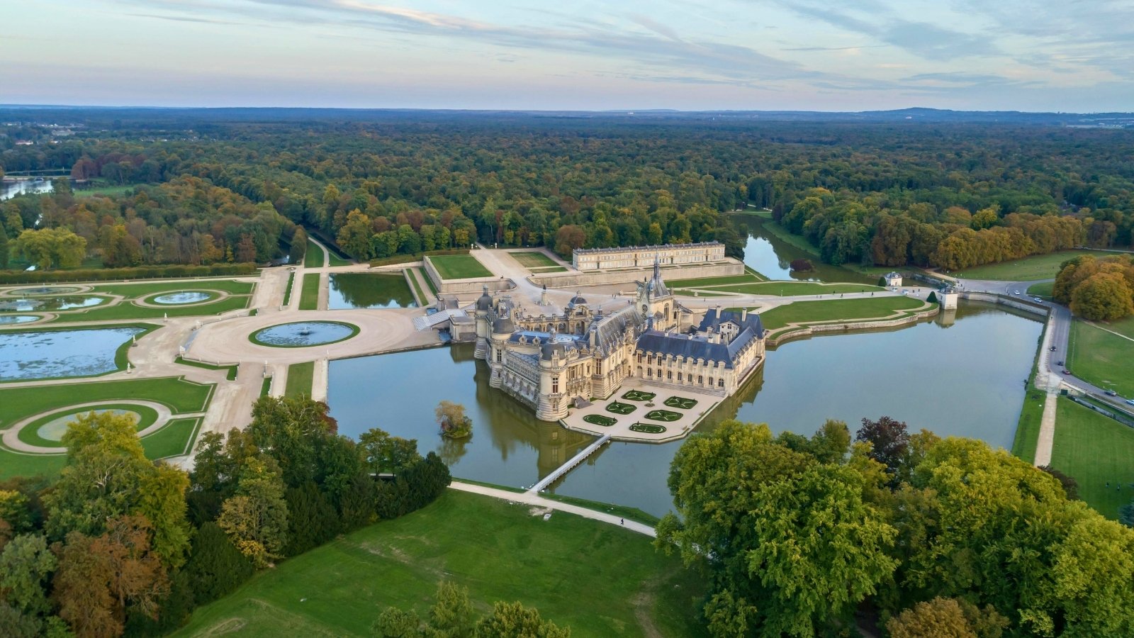 Aerial view of Chantilly Castle surrounded by gardens and moat