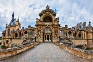 Front façade of Chantilly Castle across cobbled bridge