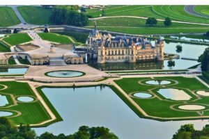 Aerial view of Chantilly Castle surrounded by formal gardens and reflective ponds