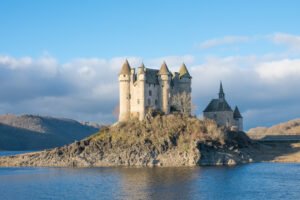 Chateau de Val perched on rocky island by blue lake