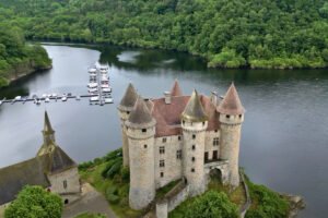 Aerial view of Chateau de Val beside forested lake and marina