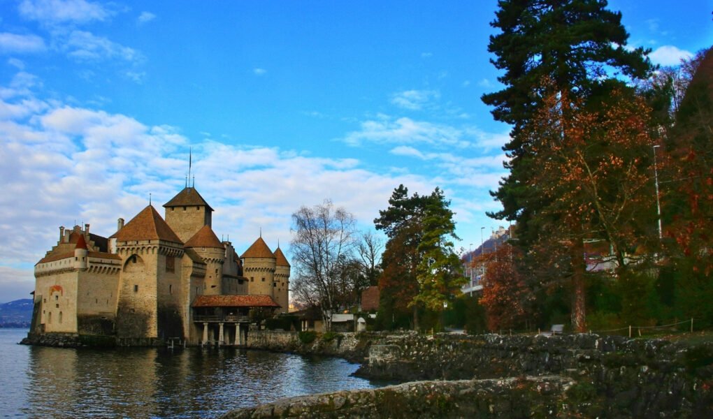 Chillon Castle by calm lake with turrets and blue sky