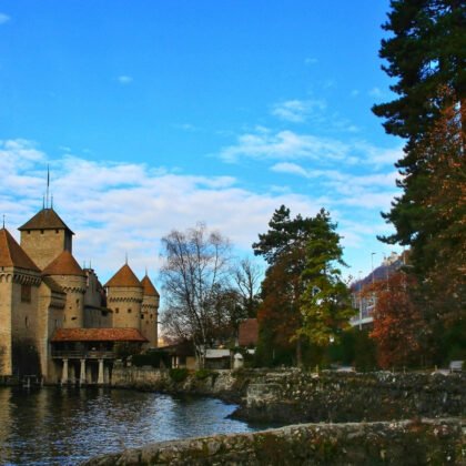 Chillon Castle by calm lake with turrets and blue sky