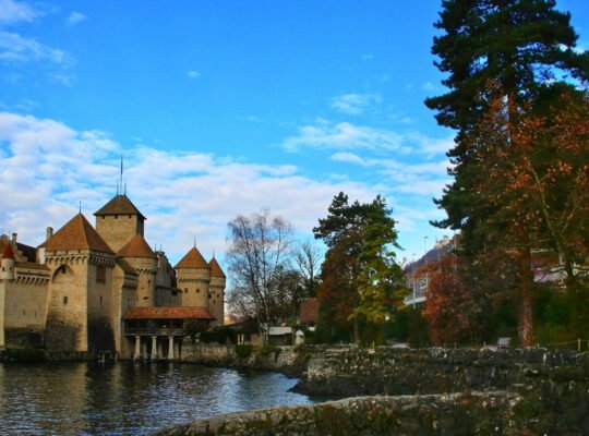 Chillon Castle by calm lake with turrets and blue sky