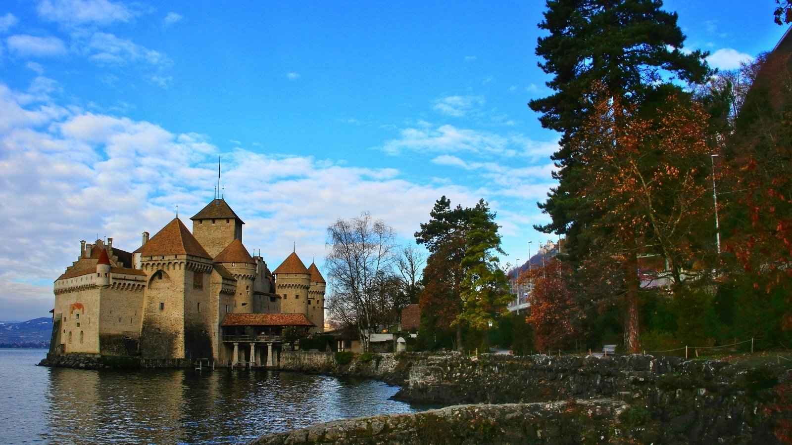 Chillon Castle by calm lake with turrets and blue sky