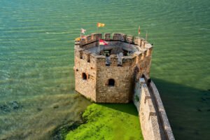 Aerial view of Golubac Fortress tower on green Danube waters