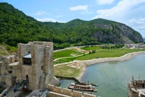 Golubac Fortress towers beside Danube with boat and green hills