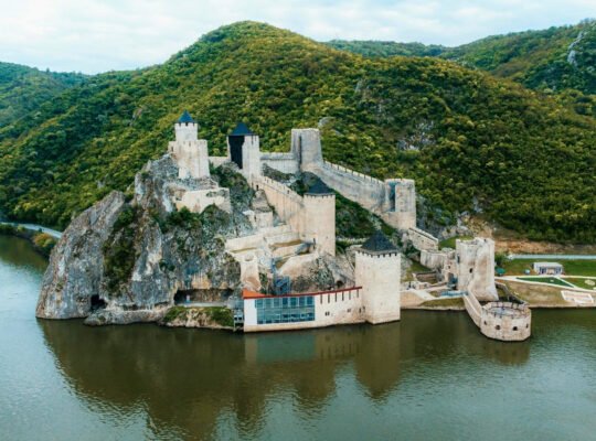 Aerial view of Golubac Fortress on river surrounded by green hills