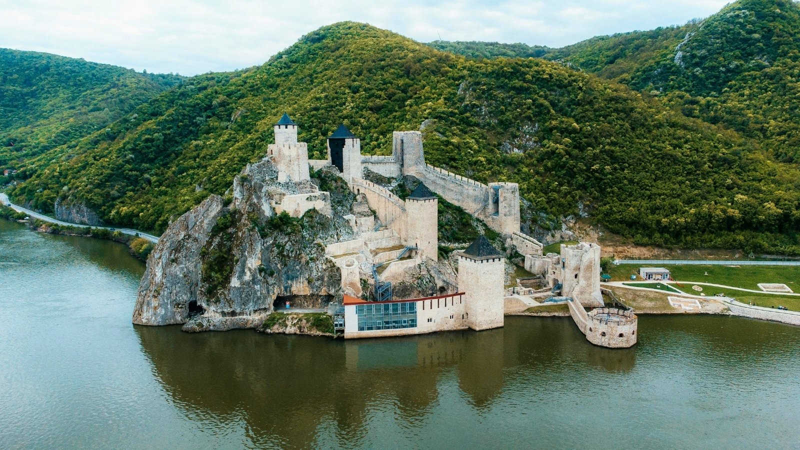 Aerial view of Golubac Fortress on river surrounded by green hills