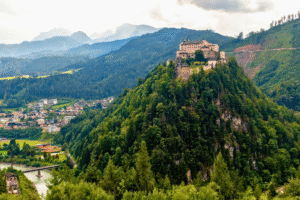 Hohenwerfen Fortress crowns a forested peak above Werfen, Austria, with river and village nestled below.