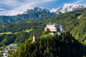 Hohenwerfen Castle on a forested cliff above Werfen, framed by snow-capped Alps in Salzburg, Austria.