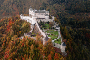 Aerial view of Hohenwerfen Castle in Werfen, Austria, surrounded by colorful autumn forests on a hilltop.