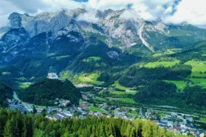 Aerial view of Hohenwerfen Castle over Werfen, Austria, framed by dramatic Alpine peaks and green valleys.