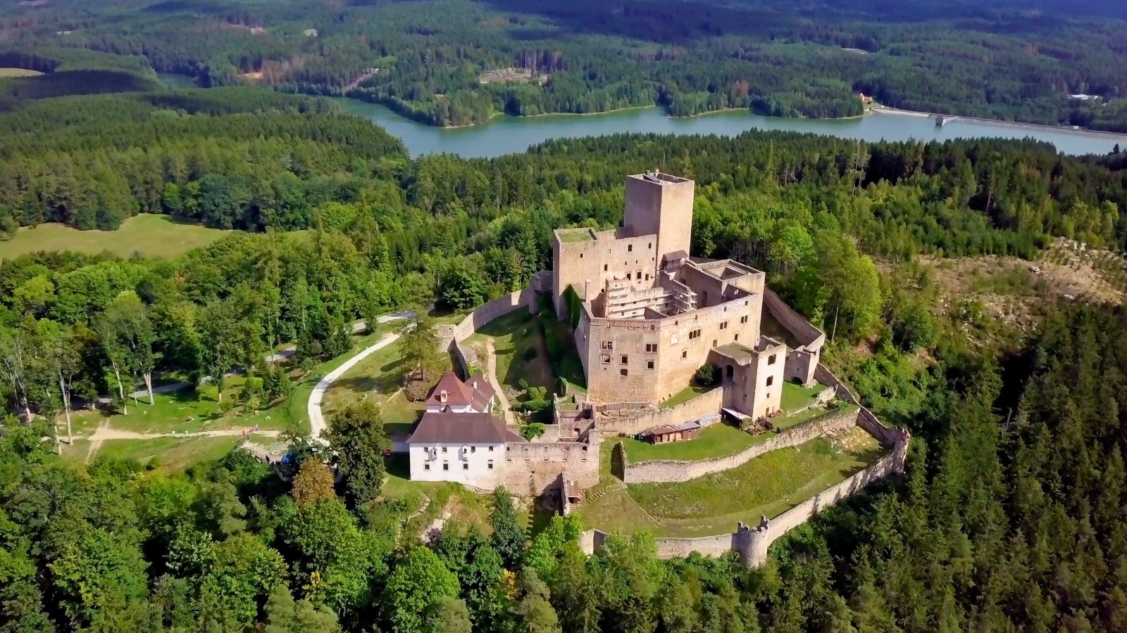 Aerial view of Landštejn Castle amid trees and reservoir