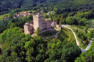 Aerial view of Landštejn Castle atop forested hill, stone walls and tower