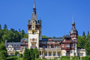 Facade of Peles Castle in Sinaia, Romania, ornate towers and timber details under a clear blue sky
