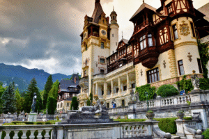 Peles Castle's ornate facade and statues against Carpathian Mountains in Sinaia, Romania.