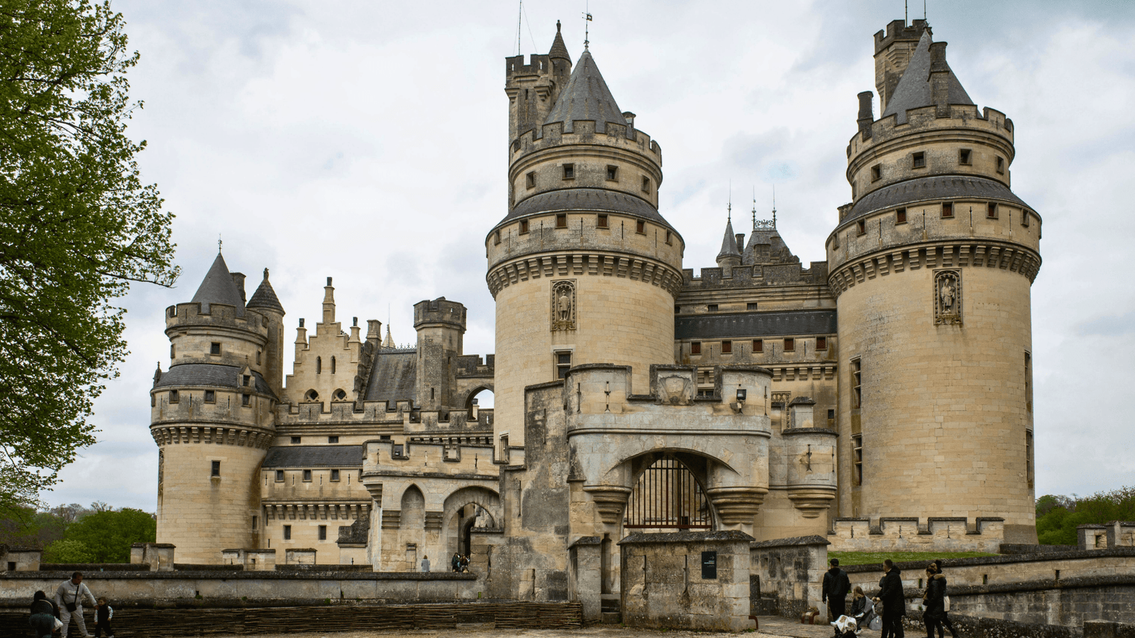 Grand towers of Château de Pierrefonds above the gatehouse on a cloudy day in Oise, France.