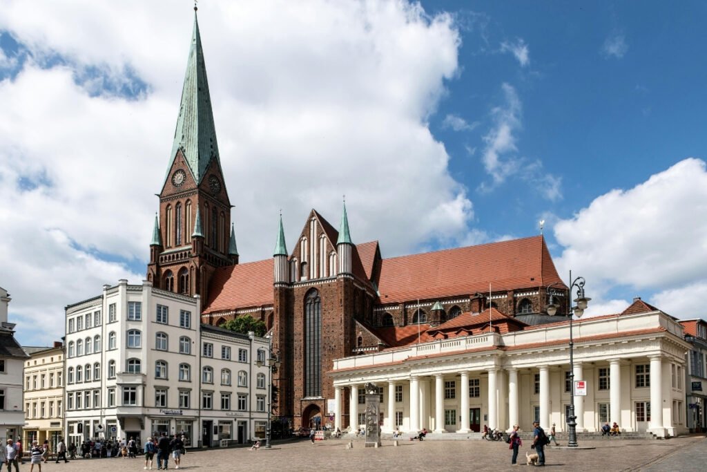 Schwerin Cathedral towering over market square with red roofs and tall copper spire