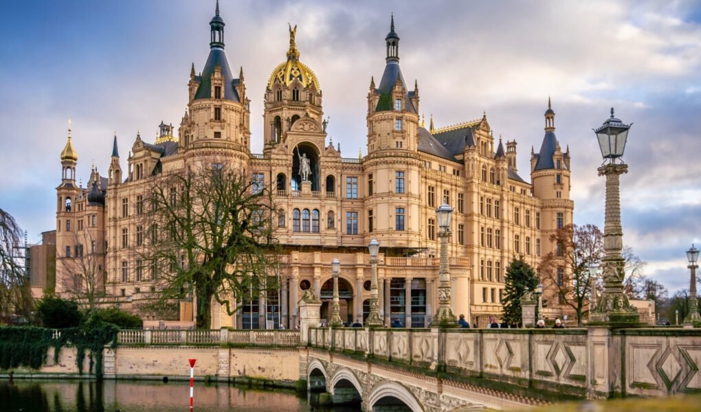Schwerin Castle reflected in calm moat with ornate bridges and towers