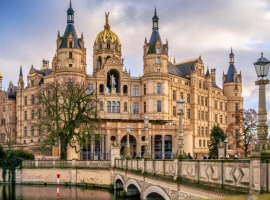 Schwerin Castle reflected in calm moat with ornate bridges and towers