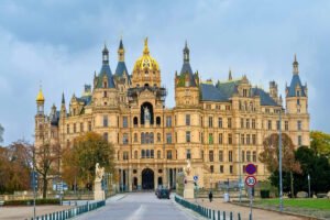 Schwerin Castle façade with golden dome and spires by a lake