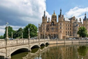 Schwerin Castle facade and lakeside bridge under cloudy sky