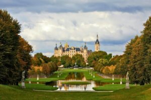 Schwerin Castle from garden path with pond reflection under cloudy sky