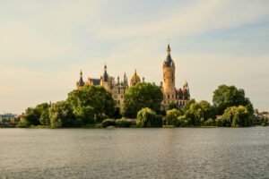 Schwerin Castle across calm lake with trees and reflective water