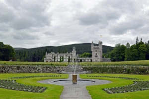 Balmoral Castle with formal garden fountain under cloudy sky