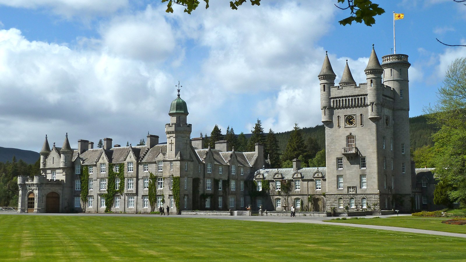 Balmoral Castle facade with turrets and manicured lawn under blue sky