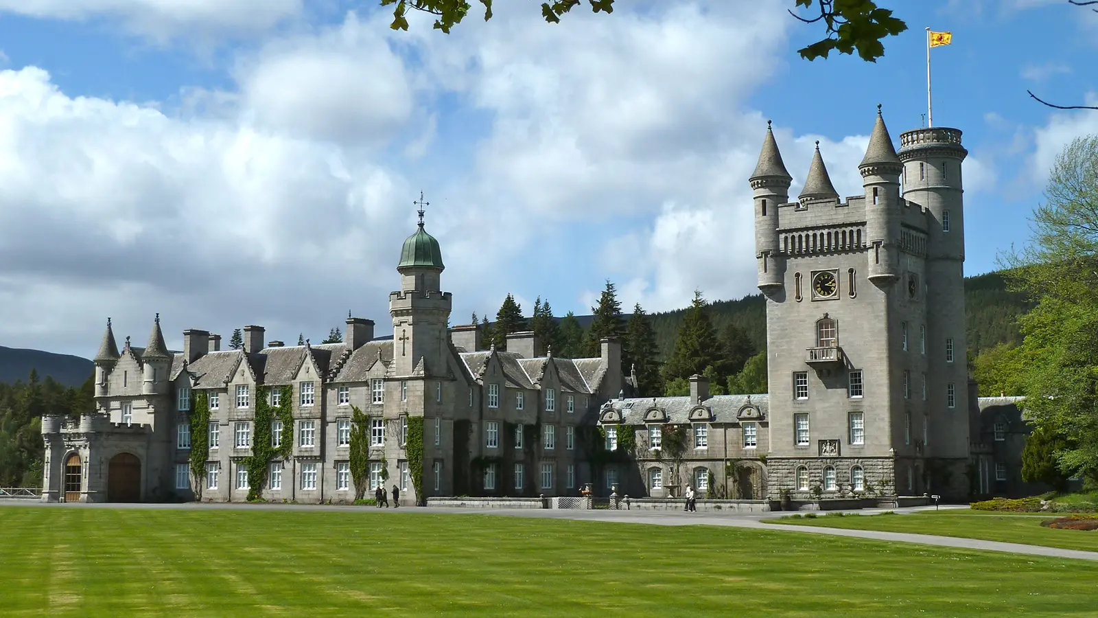 Balmoral Castle facade with turrets and manicured lawn under blue sky
