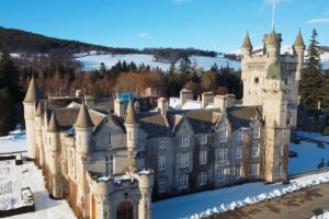 Aerial view of Balmoral Castle surrounded by snow and pine forests