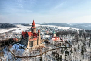 Aerial view of Bouzov Castle with snow-covered red roofs